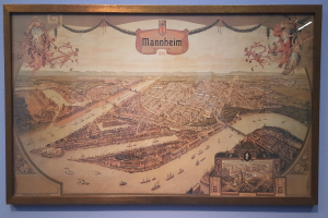 Bild eines lebendigen Stadtpanoramas in einem Museum mit klassischem Rahmen und sichtbaren Details.