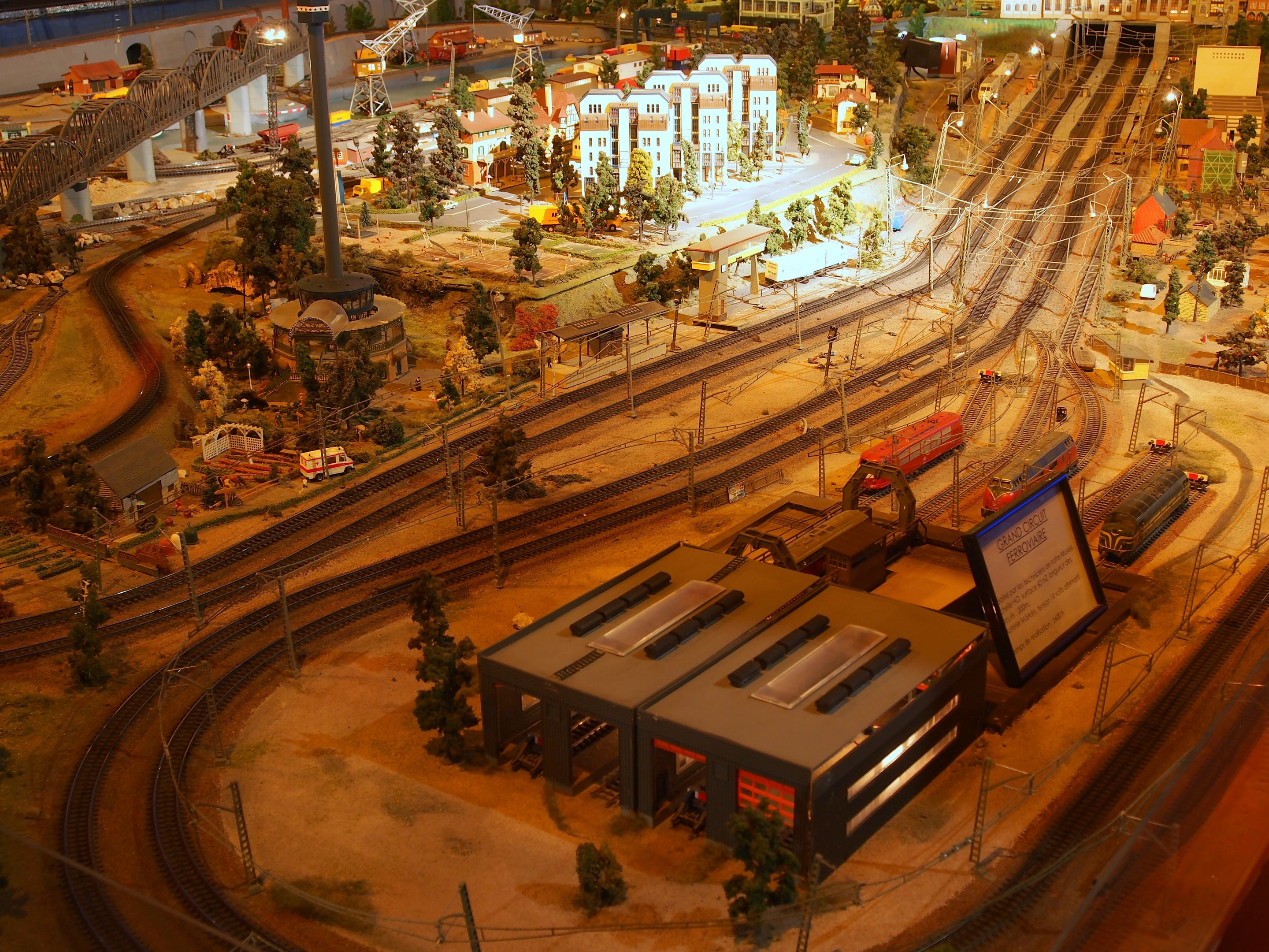 Ein detailliertes Miniaturstadt-Modellbahn-Display in einem Museum, das Gebäude, Bäume, Eisenbahnschienen, Fahrzeuge, Pfosten, Lichter und andere Gegenstände enthält.