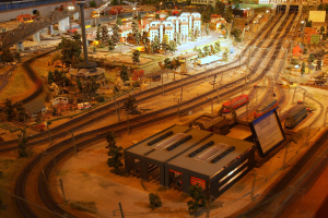 Ein detailliertes Miniaturstadt-Modellbahn-Display in einem Museum, das Gebäude, Bäume, Eisenbahnschienen, Fahrzeuge, Pfosten, Lichter und andere Gegenstände enthält.