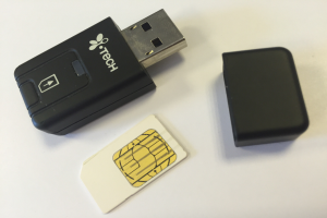 Ein schwarzer USB-Stick und eine weiße SIM-Karte liegen nebeneinander auf einer weißen Oberfläche.