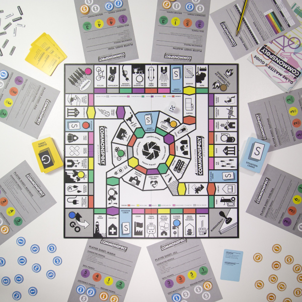 Ein Monopoly-Brettspiel auf einem Tisch mit Spielkarten, Papieren und einem Bleistift, der um das zentrale Spielbrett verstreut ist.