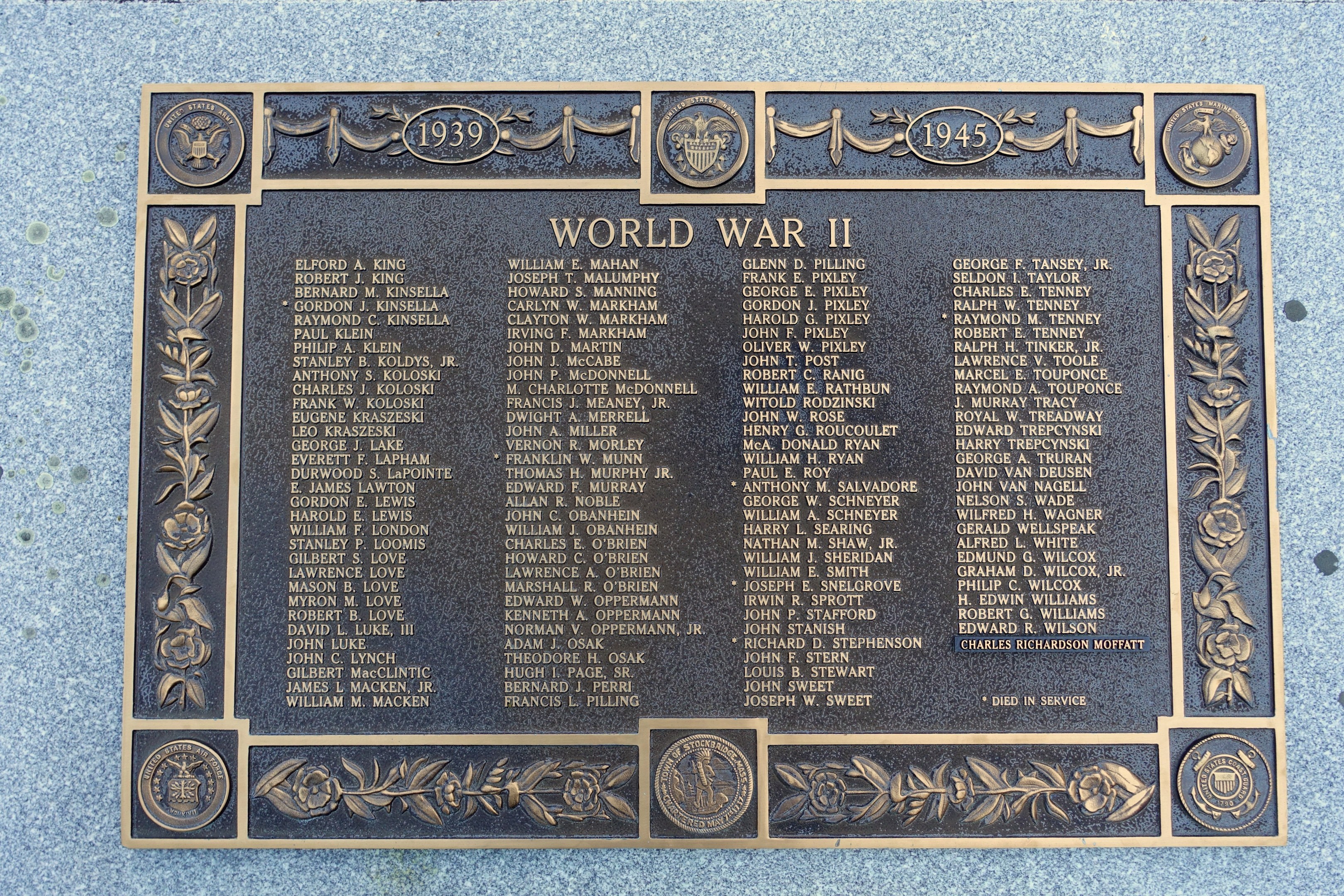 Steintafel an einer Gebäudeseite mit 'Zweiter Weltkrieg' eingraviert.