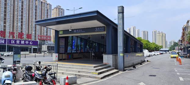 Eine belebte Stadtstraße mit einer Bushaltestelle, hohen Wolkenkratzern, geparkten Motorrädern, Verkehrskegeln, Straßenlaternen, Namensschildern, Bäumen und einem bewölkten Himmel.
