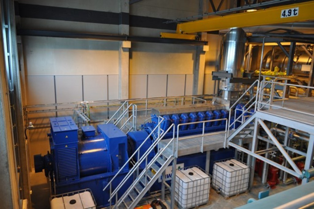 Eine Fabrikinnenszene mit Tr"gern, Treppe, Gel"nder, Containern, Lichtern, Rohren und W"nden.