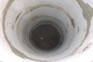 Betonsielrohr mit mittigem Loch und einem Objekt darin, umgeben von einer Betonwand.