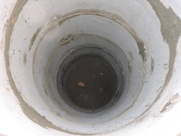 Betonsielrohr mit mittigem Loch und einem Objekt darin, umgeben von einer Betonwand.