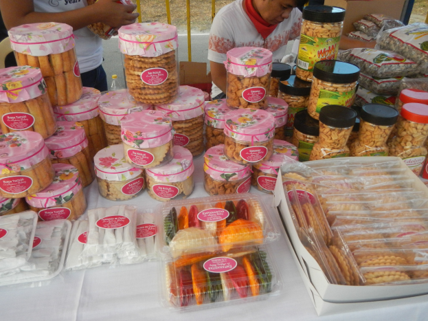 Eine Gruppe von Menschen umringt einen Tisch mit verschiedenen Speisen auf einem Outdoor-Food-Festival.