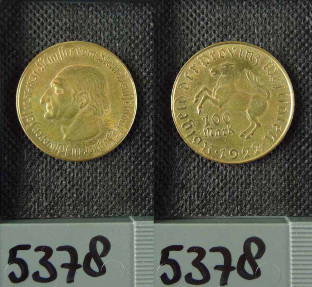 Zwei Goldmünzen aus Deutschland im Jahr 1922, jeweils mit einem Nennwert von 100 Mark, auf einer schwarzen Oberfläche mit Zahlen unten.