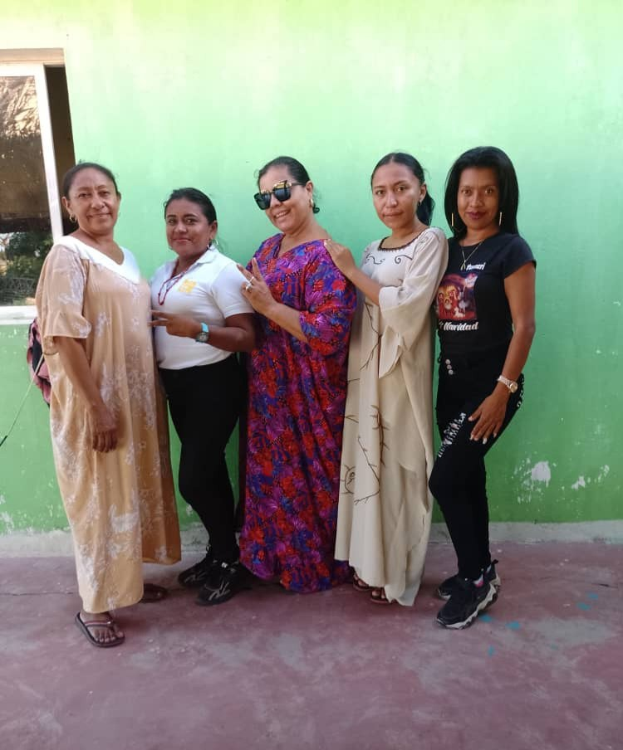 Eine Gruppe von Frauen, die vor einer grünen Wand mit einem Fenster auf der linken Seite stehen und an einem Internationaler Frauentag-Event teilnehmen.