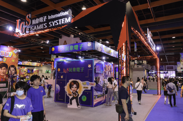Eine Gruppe von Menschen durchquert eine Messehalle mit Ständen, trägt Taschen und hält Gegenstände, mit vielen anderen im Hintergrund auf einer Gaming-Messe in China.