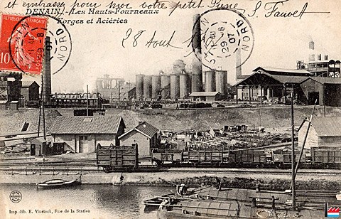 Alte Postkarte mit einer Fabrik im Hintergrund, Häusern, Strommasten, Schiffen und Wasser, mit Stempeln und Text.