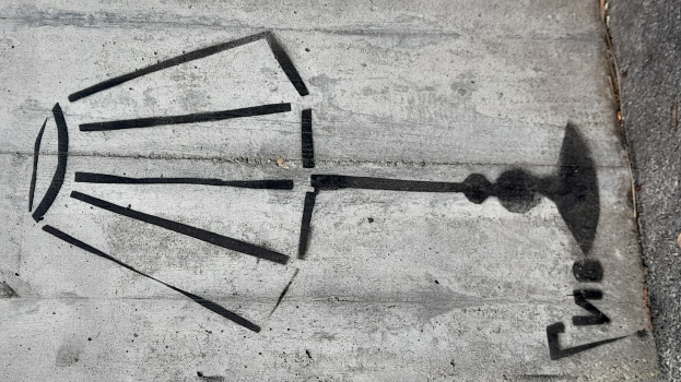 Eine Schwarz-Weiß-Zeichnung einer Glühbirne auf einem Betonboden, mit einer Straße auf der rechten Seite.