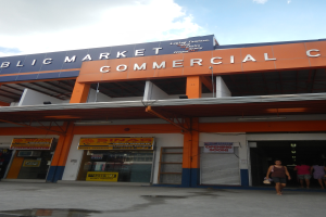 Ein öffentlicher Markt mit Menschen davor, Text auf dem Gebäude und Himmel oben.