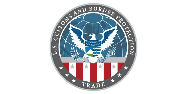 Logo des U.S. Customs and Border Protection Trade, das einen blauen Kreis mit einem weißen Stern, eine weiße Taube mit ausgebreiteten Flügeln und den Text "U.S." über der Taube zeigt, alles auf einem weißen Rand.