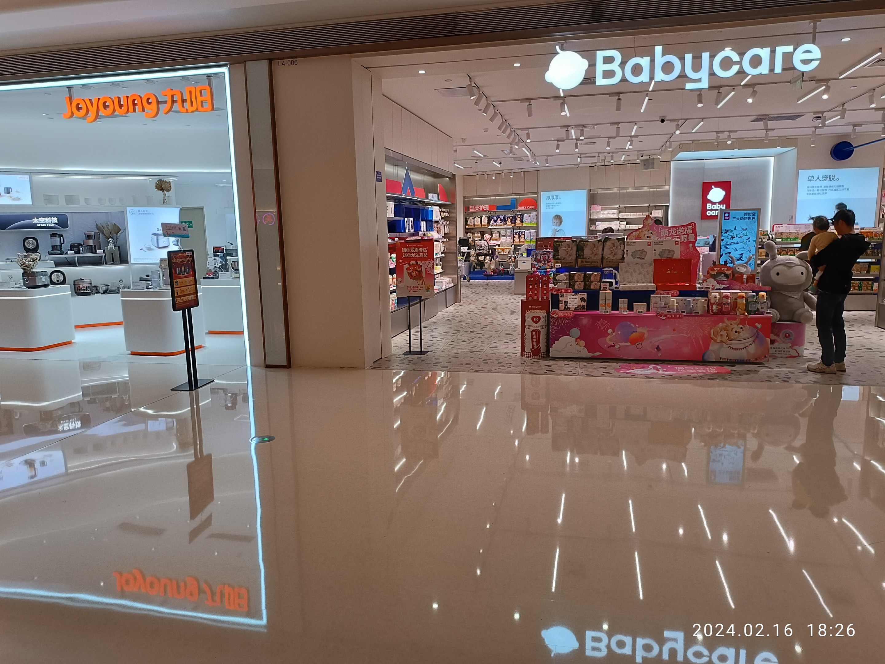 Ein Babyladen im Mall of Asia mit Regalen voller Artikel, Schildern, einem Display, Deckenleuchten und einer Gruppe von Menschen umgeben von Spielzeug.