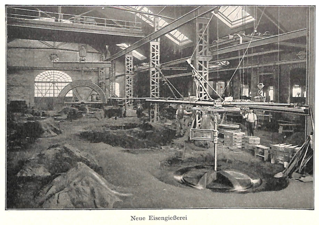 Schwarzes und weißes Foto einer Fabrikinnenszene mit Arbeitern, die Maschinen bedienen, Metallstangen und -pole, mit der Beschriftung 'Neue Eisenglebeerei, die erste Fabrik in Deutschland' unten.