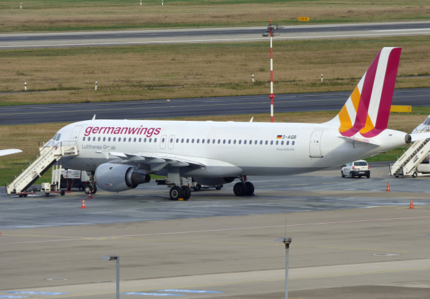 Germanwings Airbus A320-200 am Frankfurt Airport mit Bodenfahrzeugen, Verkehrskegeln, Versorgungsmasten und Grünfläche im Hintergrund.