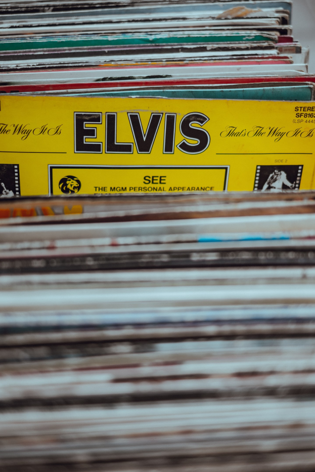Stapel von Elvis-Presley-Platten, ordentlich übereinander gestapelt auf einem Tisch mit sichtbaren Titeln und leicht unscharfem Hintergrund.