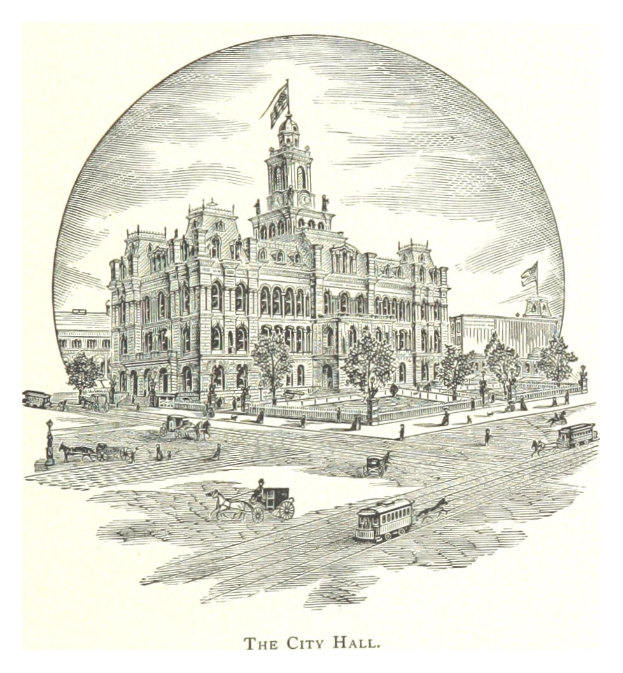 Ein großes Gebäude mit einem Glockenturm, umgeben von Bäumen und Menschen, mit Fahrzeugen auf der Straße davor, beschriftet unten.