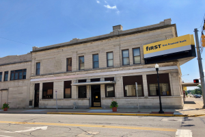 Großes Gebäude mit "First Financial Bank"-Schriftzug, umgeben von Straßeninfrastruktur, Fahrzeugen, Grünflächen und bewölktem Himmel.